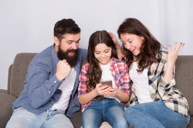 Çocuk anne ve babasıyla haber paylaşmak. Küçük kız çocuk ebeveynleri ile cep telefonu kullanın. Evde mutlu bir aile. Çocuk çocukluk mutluluğu ile. Sakallı erkek ve kadın çocuk ile. Çok eğlenceli