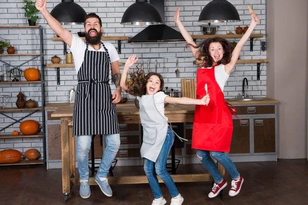 Home party. Happy family jump. Father, mother and child chef cooking. Little girl with parents in apron. Mother and father with little girl. Family day. Happy family in kitchen. Happy family morning