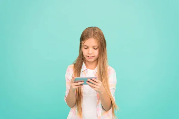 Мобильная зависимость гаджета. Девочка маленькая девочка улыбается держать смартфон. Интернет-серфинг и социальные сети. Проблема молодежи. Мобильные телефоны и интернет-зависимость. Дополнение к интернет-играм — стоковое фото