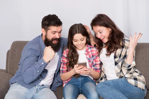 Dítě sdílet novinky s matkou a otcem. Malá dívka dítě používat mobilní telefon s rodiči. Šťastná rodina doma. Dítě s dětství štěstí. vousatý muž a žena s dítětem. Tolik zábavy — Stock fotografie