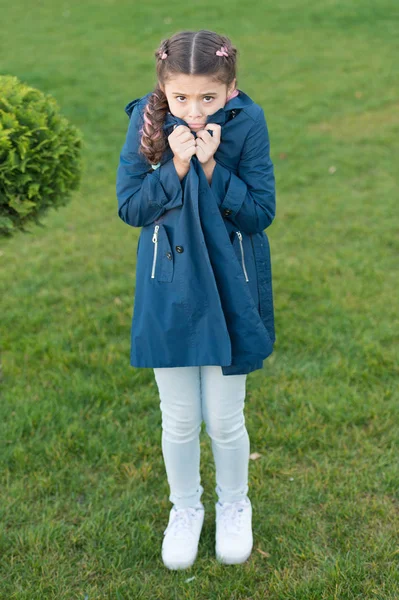 Menina bonito rosto trançado cabelo posando casaco no parque de primavera. Roupa para passeios de primavera. Um pequeno modelo de moda. Roupas e acessórios. O miúdo usa casaco de trincheira. Casaco de primavera. Deve ter um conceito. Casaco elegante — Fotografia de Stock