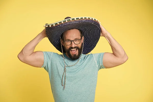 Mexican party. Man on smiling face in sombrero hat celebrating, yellow background. Guy with beard looks festive in sombrero. Fest and holiday concept. Man in festive mood at party celebrating