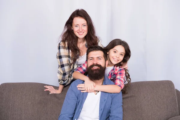 Los abrazos son totalmente devueltos. El hombre y la mujer barbudos aman a su hija. Padre, madre e hijo en casa. Día de la familia. La niña ama a sus padres en casa. Día de los niños. Familia feliz. Amor y confianza — Foto de Stock