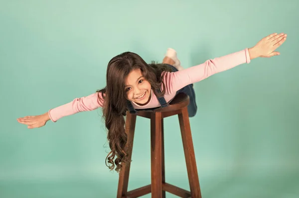 Suivez-moi. Jeune fille joyeuse imiter avion volant. Enfant jeu voler comme avion avec les mains écartées. Enfant profiter de l'enfance avec des jeux. Fille rêvant voler dans l'avion, fond turquoise — Photo