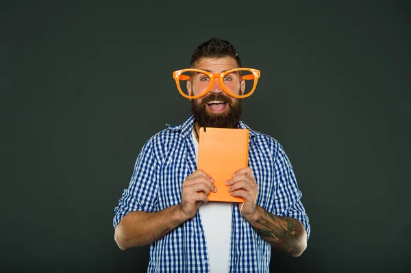 Nerdy και αστεία. Αρσενικό φοιτητής πανεπιστημίου με σημειώσεις. Μελέτη σπασίκλα βιβλίο εκμετάλλευση. Σπασίκλα βιβλίο φορώντας φανταχτερά γυαλιά. Γενειοφόρος άνδρας κόμμα γυαλιά με το βιβλίο του μαθήματος — Φωτογραφία Αρχείου
