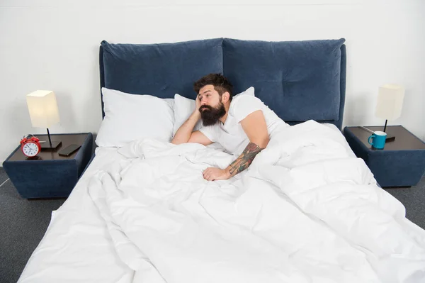 Uyku bozuklukları kavramı. Adam sakallı hippi uyku ile ilgili sorunlar yaşıyorsanız. Yatakta yatan adam rahatla ve uykuya çalışın. Gevşeme teknikleri. Uyku ve uyanıklık ihlali. Uykusuzluk — Stok fotoğraf