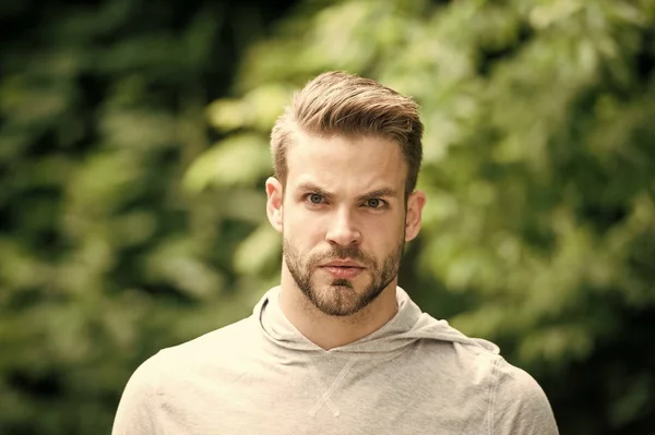 Macho avec barbe sur le visage non rasé sur le paysage naturel. Homme barbu avec un regard sérieux sur l'air frais. Je fais une pause. Décontracté dans le style. Charmant sportif. — Photo