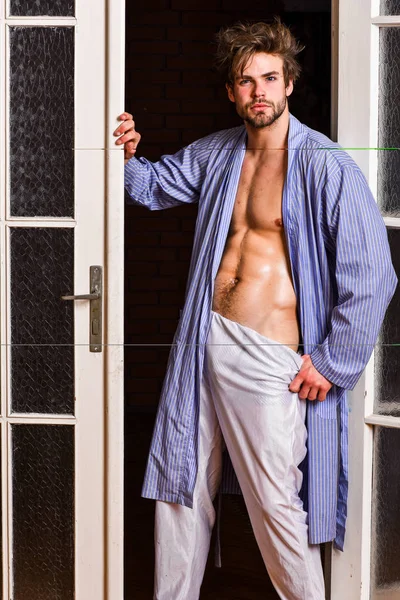 Sexy attractive macho tousled hair coming out through bedroom door. Bachelor sexy body chest and belly. Guy shimmering sweaty skin wear bathrobe. Man athlete with fit sexy torso. Sexy lover concept