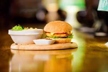 Hamburger ve patates kızartması ve domates sosu ahşap tahta üzerinde. Fast food kavramı. Burger peynir et ve salata. Yemek dolandırıcı. Susam ile lezzetli burger. Burger menü. Yüksek kalorili atıştırma