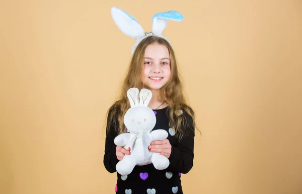 Hare is a symbol of fertility and spring. Small kid getting white hare gift on Easter day. Little girl holding Easter hare toy. Happy child playing with cute Easter hare