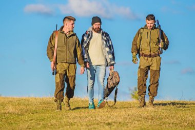 Grup erkek avcılar veya gamekeepers doğa arka plan mavi gökyüzü. Çocuklar için avcılık toplandı. Erkek av tüfekleri taşırlar. Hobi ve eğlence avcılık. Avcılar silahlı güneşli sonbahar gün yürür, yürür. Acımasız hobi