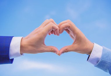 Kalp şekli hareketi simgesinin aşk ve romantizm erkek elinde. Aşk sembolü kavramı. El kalp hareketi parmaklarını kullanarak şekil oluşturur. Kalp şekli mavi gökyüzü arka planda bir alkış