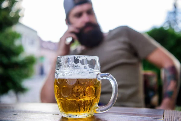 Man sit cafe terrace enjoying beer defocused. Alcohol and bar concept. Craft beer is young, urban and fashionable. Distinct beer culture. Mug cold fresh beer on table close up. Creative young brewer