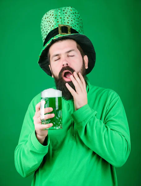 在啤酒酒吧庆祝圣客请日。带着胡子的人向圣德马克的日子敬酒。希普斯特戴着绿色的小妖精帽, 拿着啤酒杯。爱尔兰男人的胡子喝绿色啤酒。他打了个哈欠祝你好运 — 图库照片