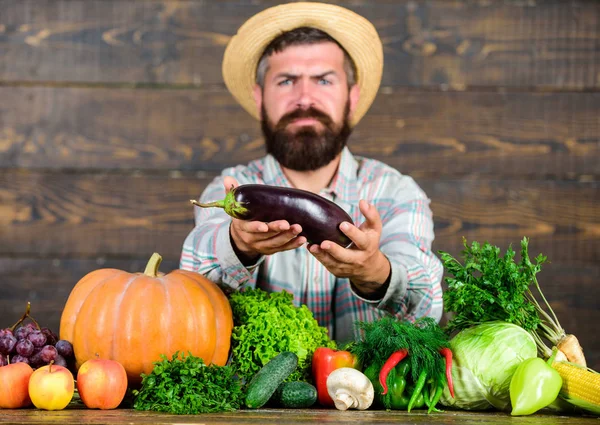 Raccolta di ottima qualità. I fertilizzanti biologici rendono il raccolto sano e ricco. Coltivatore con raccolto di verdure fatte in casa. Controllo biologico dei parassiti. Uomo con la barba orgoglioso del suo raccolto sfondo in legno — Foto Stock