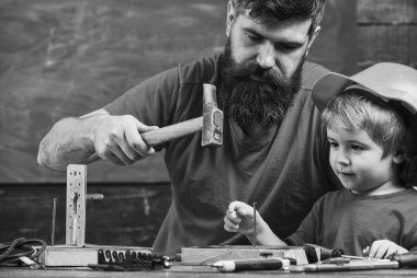 Atölye ve tamirci kavramı. Çocuk, Çocuk koruyucu kask hobnails baba ile çekiç için öğrenme içinde meşgul. Baba, sakallı hobnails ve çekiç kullanmak için küçük oğlu öğretim üst