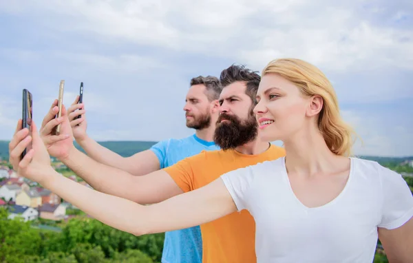 Experimentar el intercambio digital de imágenes. Mejores amigos tomando selfie con el teléfono de la cámara. Gente disparando selfie en la naturaleza. Mujer sexy y hombres sosteniendo teléfonos inteligentes en las manos. Compartir selfie en las redes sociales — Foto de Stock