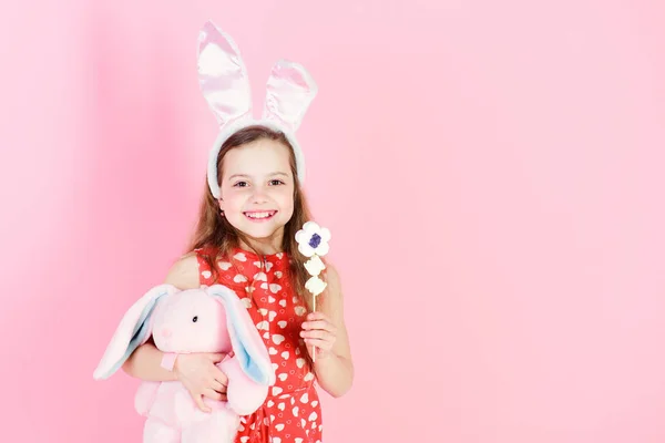 女孩微笑与棒棒糖糖果和兔子在粉红色的背景 — 图库照片