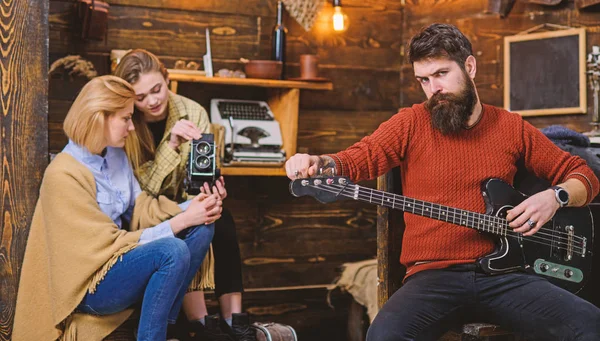 Mamá y chica adolescente grabando actuación musical en cámara de video. Músico de rock acariciando instrumento favorito. Hombre barbudo con mirada brutal tocando la guitarra. Hombre con barba de moda ensayando melodía — Foto de Stock