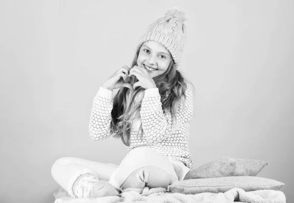 Prevent winter hair damage. Winter hair care tips you should follow. Child long hair smiling show heart gesture. Girl wear knitted hat pink background. Look after scalp and hair this winter