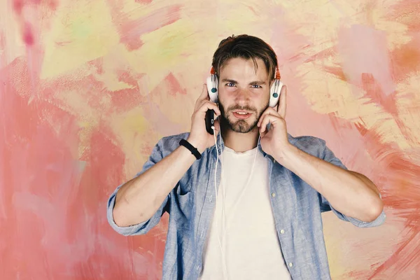 Hipster de ojos azules con estilo y smartphone. Americano guapo barbudo con auriculares. Hombre europeo divertirse. Alegre adolescente dj escuchar canciones a través de auriculares. Estilo de vida musical — Foto de Stock