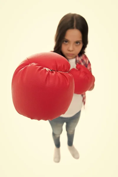 La educación feminista. Todas las chicas deberían saber cómo defenderse. Chica entrenando seriamente guantes de boxeo. El rostro concentrado del niño con guantes deportivos practica habilidades de lucha aisladas blancas. Las niñas poder — Foto de Stock