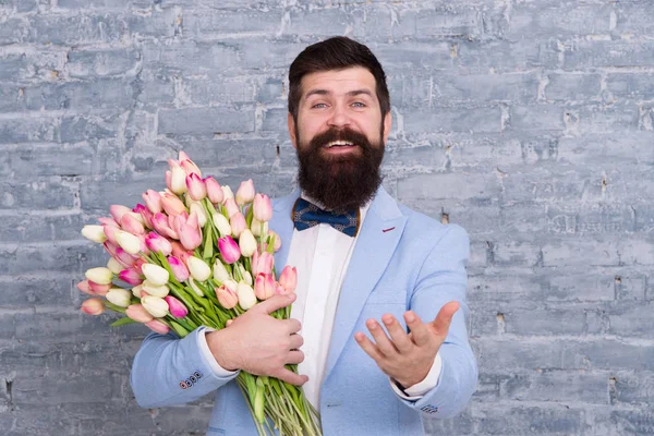 Macho getting ready romantic date. Tulips for sweetheart. Romantic gift. Man well groomed tuxedo bow tie hold flowers bouquet. How to be gentleman. Guide for modern man. Romantic man with flowers