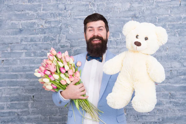 Feliz dia de primavera. um homem apaixonado. Um presente de primavera. Homem barbudo hipster com flores. Homem barbudo com buquê de tulipa, urso. Encontro amoroso. férias internacionais. Flor para 8 de março. Dia das mulheres. Homem barbudo feliz — Fotografia de Stock