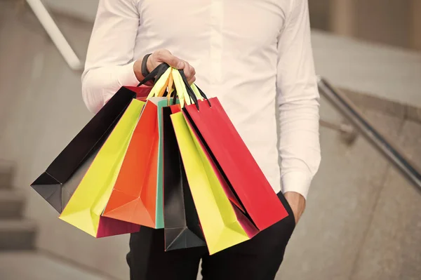 Bunch of shopping bags in male hands outdoor, close up. Shopping tips. Successful shopping expedition. What a waste. Buy with list to not overspend and waste time. Plan your purchases in advance