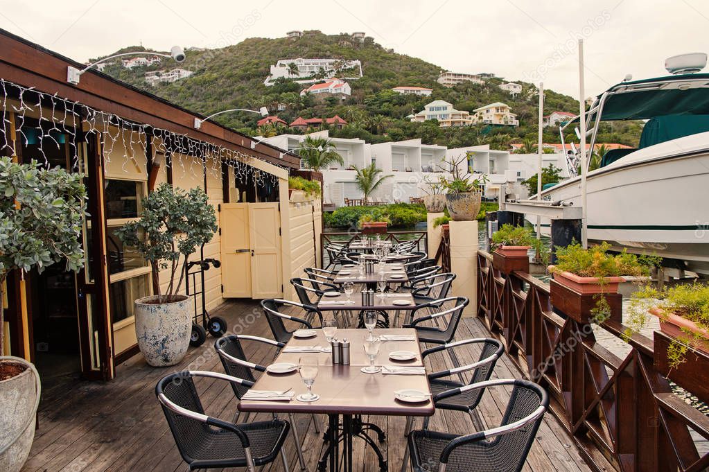 Restaurant open air in philipsburg, sint maarten. Terrace with tables, chairs and yacht in sea. Eating and dining outdoor. Summer vacation at Caribbean island, travelling. Enjoy life concept