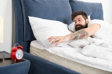 Yine uyuya kalmışım. Erken uyanma için ipuçları. Adam hipster uykulu yüz yatak çalar saat ile sakallı. Bu zil dön. Ne korkunç gürültü. Sorun sabah erken uyanma. Çalar saat ile ayağa kalk