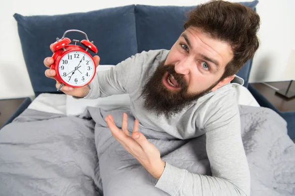 Tips for waking up early. Man bearded hipster sleepy face waking up. Daily schedule for healthy lifestyle. Alarm clock ringing. Hate this noise. Problem with early morning awakening. Get up early
