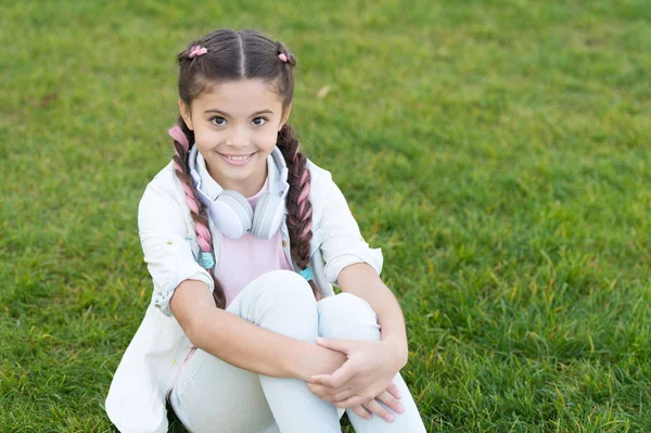 Humor de primavera. Jogador de Mp3. A menina ouve música. menina feliz. Livro áudio. Um miúdo com auscultadores. Criança elegante relaxar na grama verde. Primavera na minha cabeça. Estilo primavera. Desfrute do descanso da primavera. espaço de cópia — Fotografia de Stock