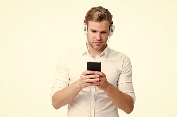 Switch radio channel. Man listening favourite song headphones with smartphone. Guy earphones listens music. Man concentrated face enjoy listening music isolated white background. Change radio channel