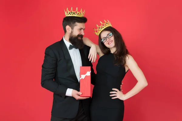 Royal traditions. Celebrate anniversary. Royal gift. King in tuxedo golden crown giving gift box to queen of his heart. Couple in love royal family. Elite society. King and queen formal event