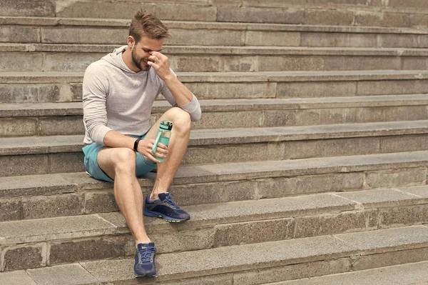 Müde nach dem Training an der frischen Luft. bleiben hydratisiert und gesund. Macho mit Wasserflasche sitzen auf Stufen, kopieren Raum. Durst. starker Mann mit Plastikflasche entspannt auf der Treppe. Sport und Fitness — Stockfoto