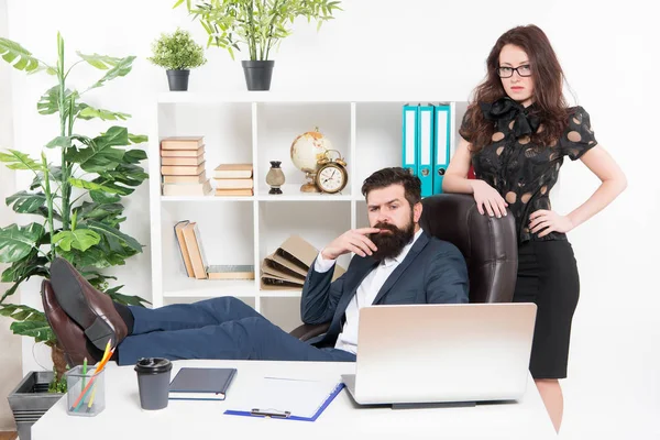 Typical office life. Man bearded hipster boss sit in leather armchair office interior. Boss and secretary girl at workplace. Relations at work. Business people and staff concept. Lazy boss office