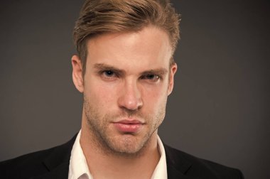 Erkeklik ve güven. Olarak, onun görünümünü kendine güvenen bir adam. Kıl ve saç modeli ile de bakımlı adam gri arka plan. Adam yakışıklı resmi takım elbise. Maço emin konsantre yüz yakın çekim