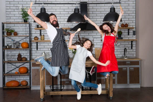 Undervisa barn mat. Helg frukost. Matlagning med barn kan vara kul. Ha kul i köket. Familj mamma pappa och lilla dotter slitage förkläden hoppa i köket. Familjen ha roliga matlagning tillsammans — Stockfoto