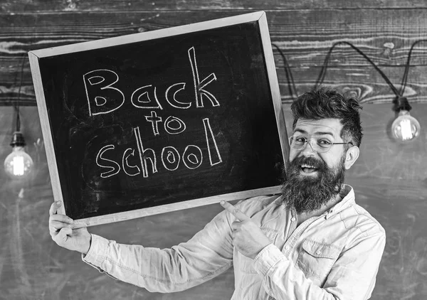 Teacher in eyeglasses holds blackboard with title back to school. Man with beard and mustache on happy face welcomes colleagues, chalkboard on background. Hiring teachers concept — Stock Photo, Image