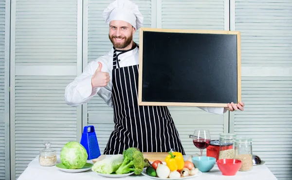 Nuestra escuela es la mejor. Hombre mostrando los pulgares hacia arriba con el tablero vacío. Educación en cocina y preparación de alimentos. Jefe de cocina enseñando clase magistral en la escuela de cocina. Maestro cocinero en la clase de cocina, espacio de copia — Foto de Stock