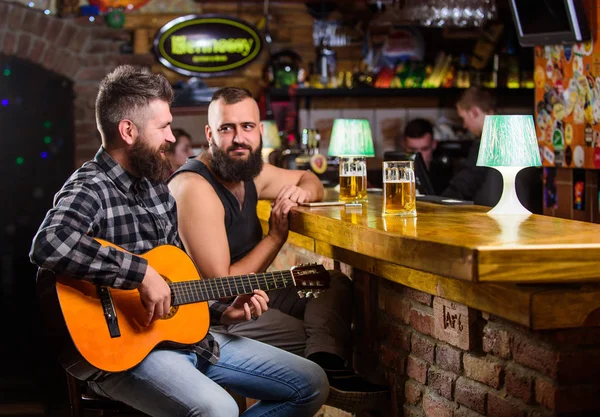 Cheerful friends relax with guitar music. Friday relaxation in bar. Friends relaxing in bar or pub. Real men leisure. Hipster brutal bearded spend leisure with friend in bar. Man play guitar in bar