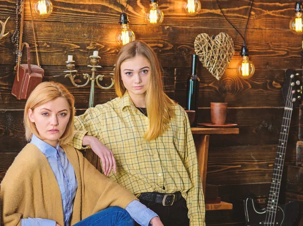 Concepto de noche conmovedor. Amigos o hermanas pasan una agradable velada en la casa de guardabosques, fondo interior. Las chicas en caras tranquilas disfrutan de un ambiente cálido mientras descansan. Chicas relajándose de vacaciones — Foto de Stock