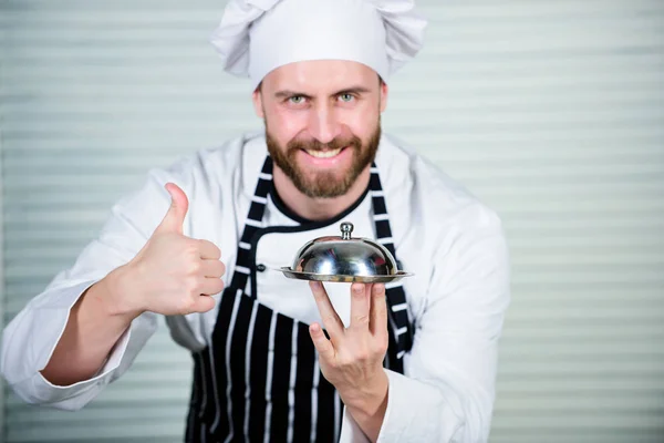 Thumbs up for the best menu. Handsome man in apron and cook hat. Master chef serving meal in restaurant. Chef cook in uniform standing with delicious dish. Casual restaurant featuring set menu