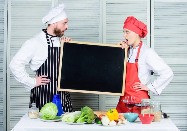 Eine Reihe von Fertigkeiten zu erwerben. Ein Ehepaar mit leerer Tafel in der Kochschule. Meisterkoch und Vorbereitungskoch geben Kochkurse. Koch und Kochhelfer unterrichten Meisterkurs, Kopierraum — Stockfoto