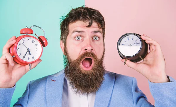 Mannen skäggig hipster håll två olika klockor. Guy orakad förbryllad ansikte har problem med att ändra tiden. Tidszon. Föränderliga tidszoner påverka hälsa. Gör ändra klockan bråka med din hälsa — Stockfoto