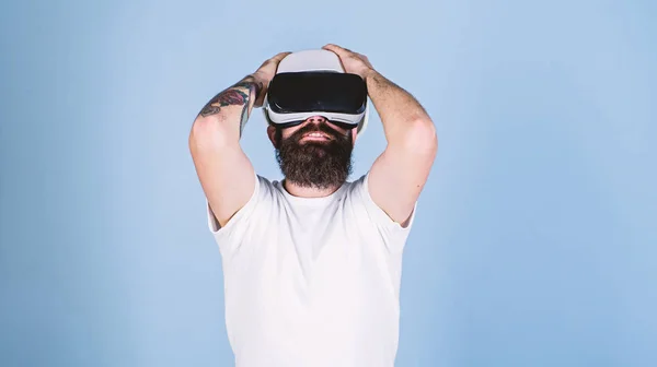 3D design concept. Architect or engineer with virtual reality glasses. Man with beard in VR glasses pleased and delighted, light blue background. Guy in helmet works as engineer in virtual reality