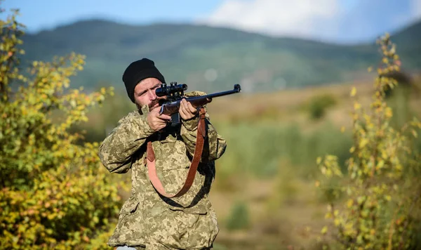 Lovecké koncept mužským koníčkem. Muž brutální hajný přírodní pozadí. Hunter držet pušku. Vousatý lovec trávit volný čas lovu. Zaměření a soustředění zkušeného lovce. Regulaci — Stock fotografie