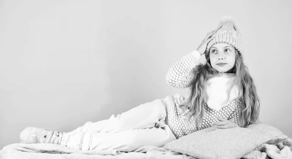 Μοντέλο μόδας χαμογελαστό παιδί. Χειμερινή Μόδα έννοια. Παιδί κορίτσι φορούν χαριτωμένο πλεκτό καπέλο μοντέρνα και άνετα ζεστά ρούχα. Μακριά μαλλιά κορίτσι χαλάρωση ροζ φόντο. Χειμερινή Μόδα για παιδιά — Φωτογραφία Αρχείου