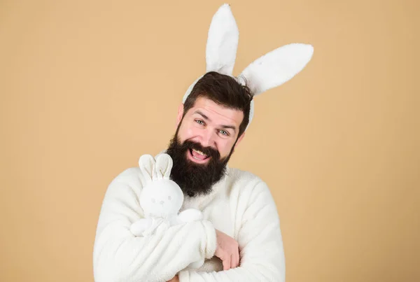 Coelho de Páscoa é um símbolo da Páscoa e estação de primavera. Hipster feliz com longas orelhas de coelho segurando coelho brinquedo. Homem barbudo em traje de coelho de Páscoa com brinquedo de lebre. Fertilidade e vida nova. Véspera de Páscoa — Fotografia de Stock